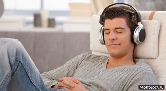 Young man relaxing with headphones, listening to music with eyes closed, smiling.